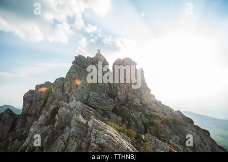 Vue lointaine du randonneur standing on mountain contre ciel nuageux Banque D'Images