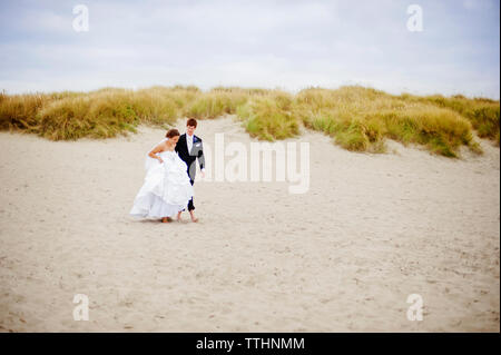 Bride and Groom walking on beach Banque D'Images