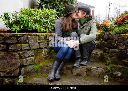 Couple rubbing noses assis étapes de jardin Banque D'Images