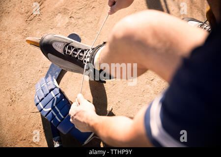 Portrait de l'homme liant les lacets des patins sur terrain Banque D'Images