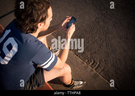 High angle view of roller hockey player using mobile phone while sitting on bench Banque D'Images