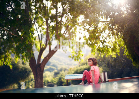 Fille assise sur le trampoline et à la suite Banque D'Images