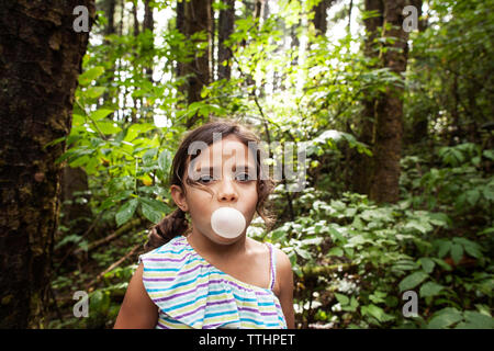 Portrait of Girl blowing bubble gum en forêt Banque D'Images