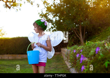 Girl in fairy costume tenue debout sur l'herbe de godet Banque D'Images