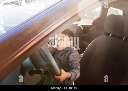 Garçon semblant de conduire tout en sitting in car Banque D'Images