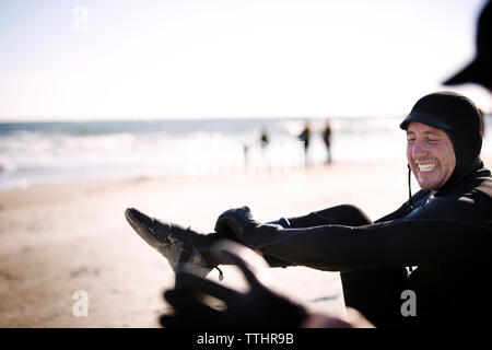 La préparation pour le surf surfer tout en étant assis sur le rivage à Beach Banque D'Images