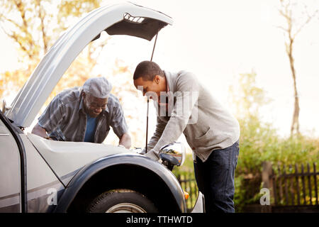 Heureux père et fils réparation voiture contre sky Banque D'Images