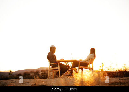 Low angle view of couple assis sur des chaises contre ciel clair Banque D'Images