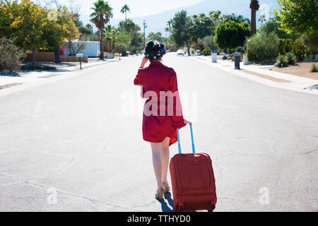 Rear view of woman with suitcase walking on street Banque D'Images