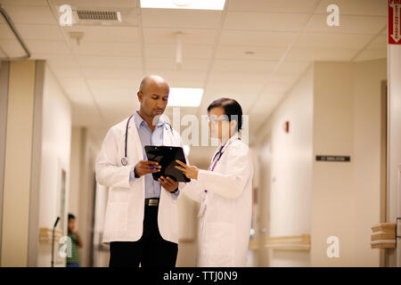 Femme médecin montrant des rapports au médecin homme debout à l'hôpital Banque D'Images