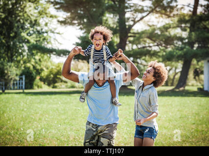 Happy father carrying son on shoulders avec fille à l'arrière-cour Banque D'Images