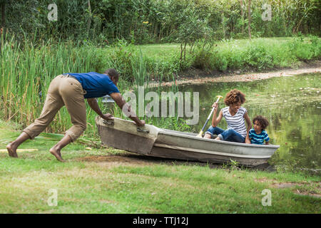 Man pushing family sitting in boat Banque D'Images