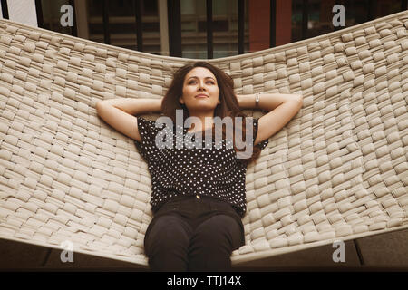 Thoughtful woman lying on hamac dans patio Banque D'Images