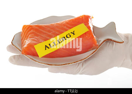 Concept alimentaire allergique. Hand in glove holding red fish isolated on white Banque D'Images