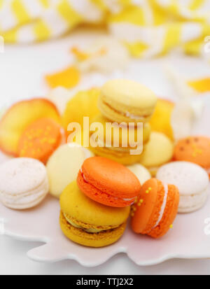 Plaque avec des macarons et des pétales de rose sur fond clair Banque D'Images