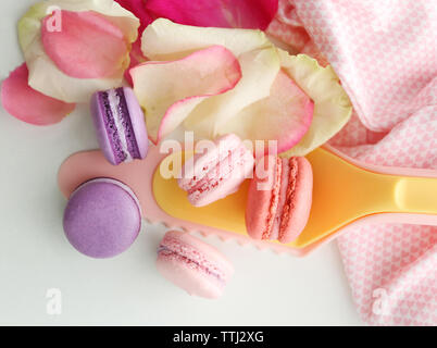 Des macarons et des pétales de rose sur fond blanc Banque D'Images