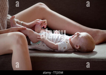 Portrait of woman Playing with baby girl on sofa at home Banque D'Images