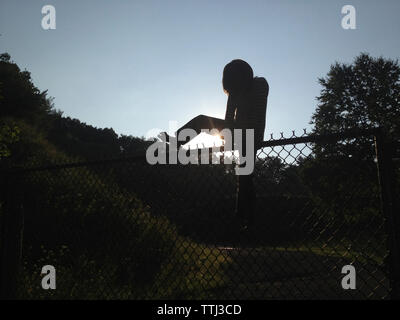 Toute la longueur de la ligne garçon acier clôture à field contre ciel bleu clair Banque D'Images