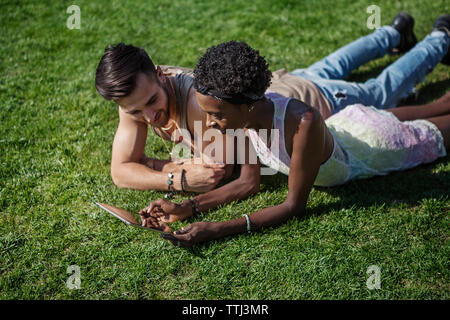 Couple using tablet computer on grassy field Banque D'Images