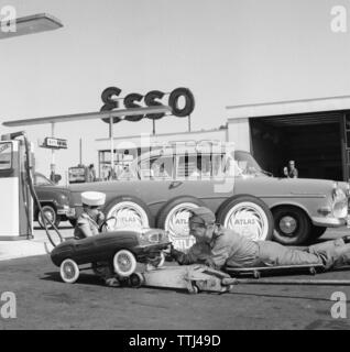 Station-service des années 50. Un garçon dans sa voiture à pédale il a entretenus à une station essence Esso. Un homme de service a levé le petit véhicule et est réparé. Suède 1958. Kristoffersson ref DC100-9 Banque D'Images