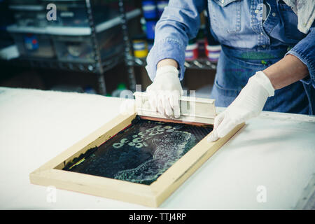 Les mains coupées à l'aide d'une raclette à l'artisane de conception d'impression sur tissu Banque D'Images