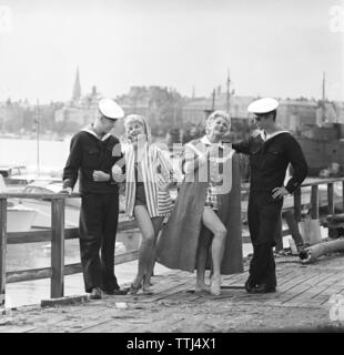 La mode des années 1950. Deux jeunes femmes portant la saison d'été dans le style de la mode. Deux marins en uniforme ajoute au thème. Suède 1958