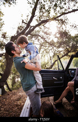 Man lifting boy alors qu'il se trouvait avec sa famille dans la forêt Banque D'Images