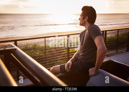 L'homme à l'écart tout en étant assis sur les pick-up pendant le coucher du soleil Banque D'Images