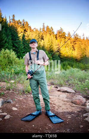 Portrait d'homme tenant la canne à pêche dans l'aménagement forestier Banque D'Images