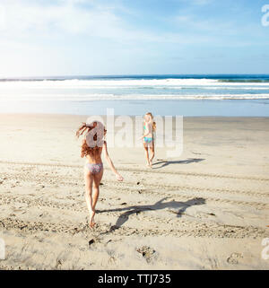 Happy friends in bikini tournant sur le rivage à Beach Banque D'Images