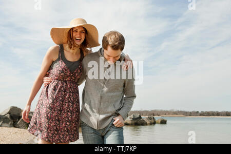 Heureux couple walking on beach against sky Banque D'Images