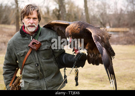 Portrait d'un homme et d'oiseau de manger tout en restant assis sur la main Banque D'Images