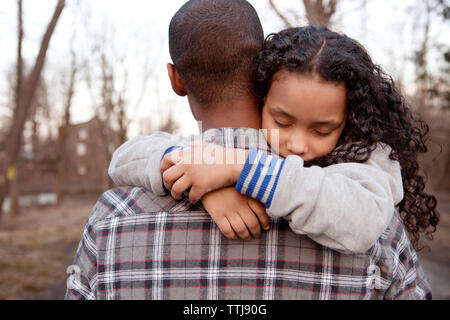 Vue arrière du père fille fatigué transportant en marchant dans la forêt Banque D'Images