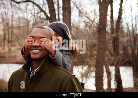 Playful girl couvrant les yeux avec les mains du père dans la forêt Banque D'Images