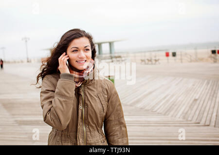 Teenage girl talking on mobile phone while standing against sky Banque D'Images