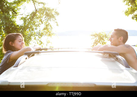 Vue latérale du couple leaning on car contre lake Banque D'Images