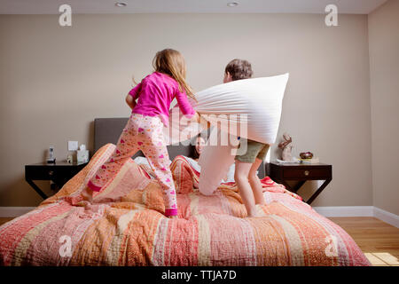 Les enfants jouant pillow fight avec les parents sur le lit chez lui Banque D'Images