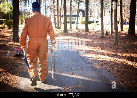 Vue arrière de l'homme exerçant son équipement de jardinage en forêt Banque D'Images