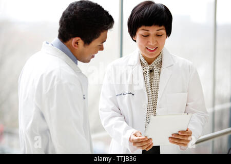 Heureux les médecins à la tablette à l'ordinateur tout en se tenant à l'hôpital Banque D'Images