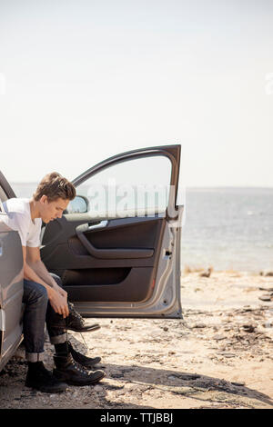 Homme portant des chaussures alors que sitting in car Banque D'Images