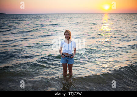 Portrait de femme avec les mains dans les poches dans l'eau at beach Banque D'Images