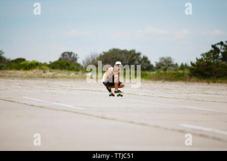 Man performing stunt sur planche sur le terrain contre le ciel Banque D'Images