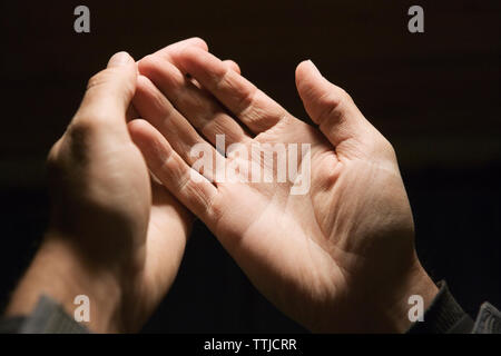 Portrait de l'homme les mains contre fond noir Banque D'Images