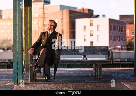 homme d'affaires regardant loin tout en étant assis sur le banc à la station de métro Banque D'Images