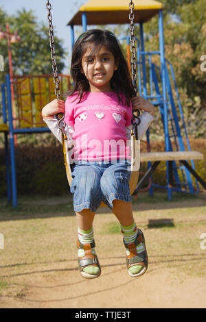 Fille se balançant dans un parc Banque D'Images