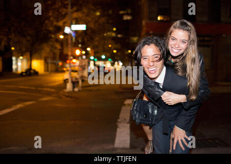 Portrait of happy man piggybacking copine debout on city street Banque D'Images