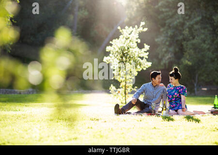 Romantic couple sitting on grassy field Banque D'Images