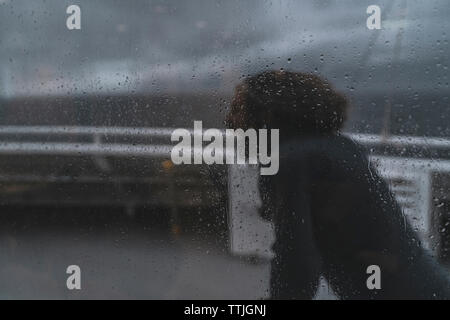 L'homme aux longs cheveux au vent marche vu à travers un voile tempête un jour de pluie. Banque D'Images