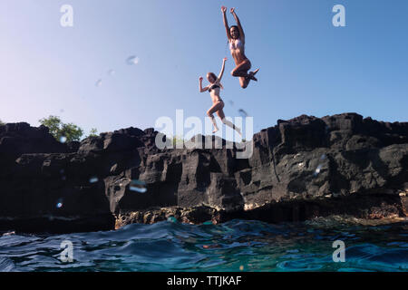 Les amis sauter de falaise dans la mer Banque D'Images