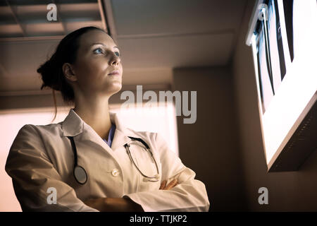 Low angle view of doctor with arms crossed looking at x-ray Banque D'Images